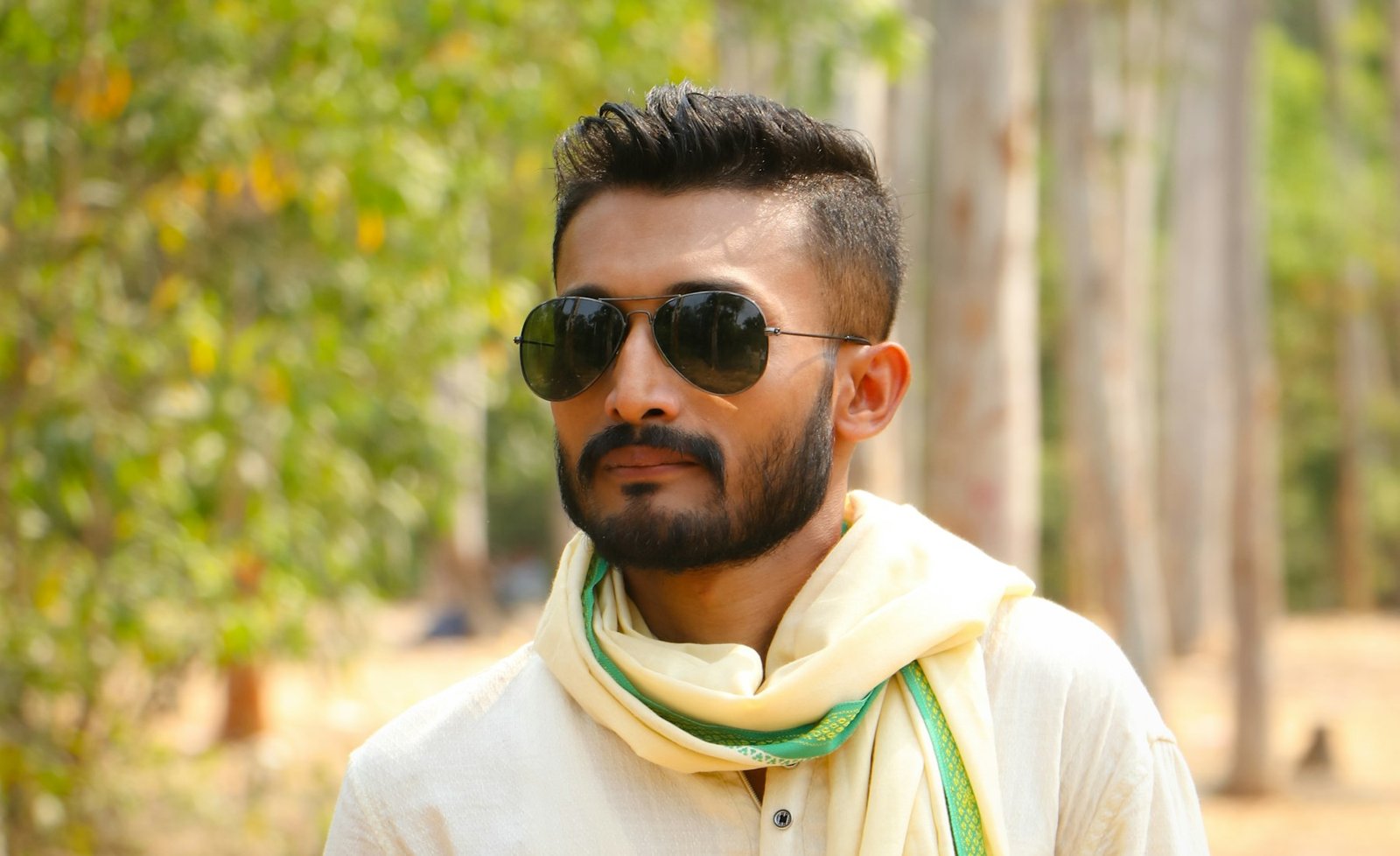Bearded Indian model outdoors wearing ivory traditional clothing and sunglasses